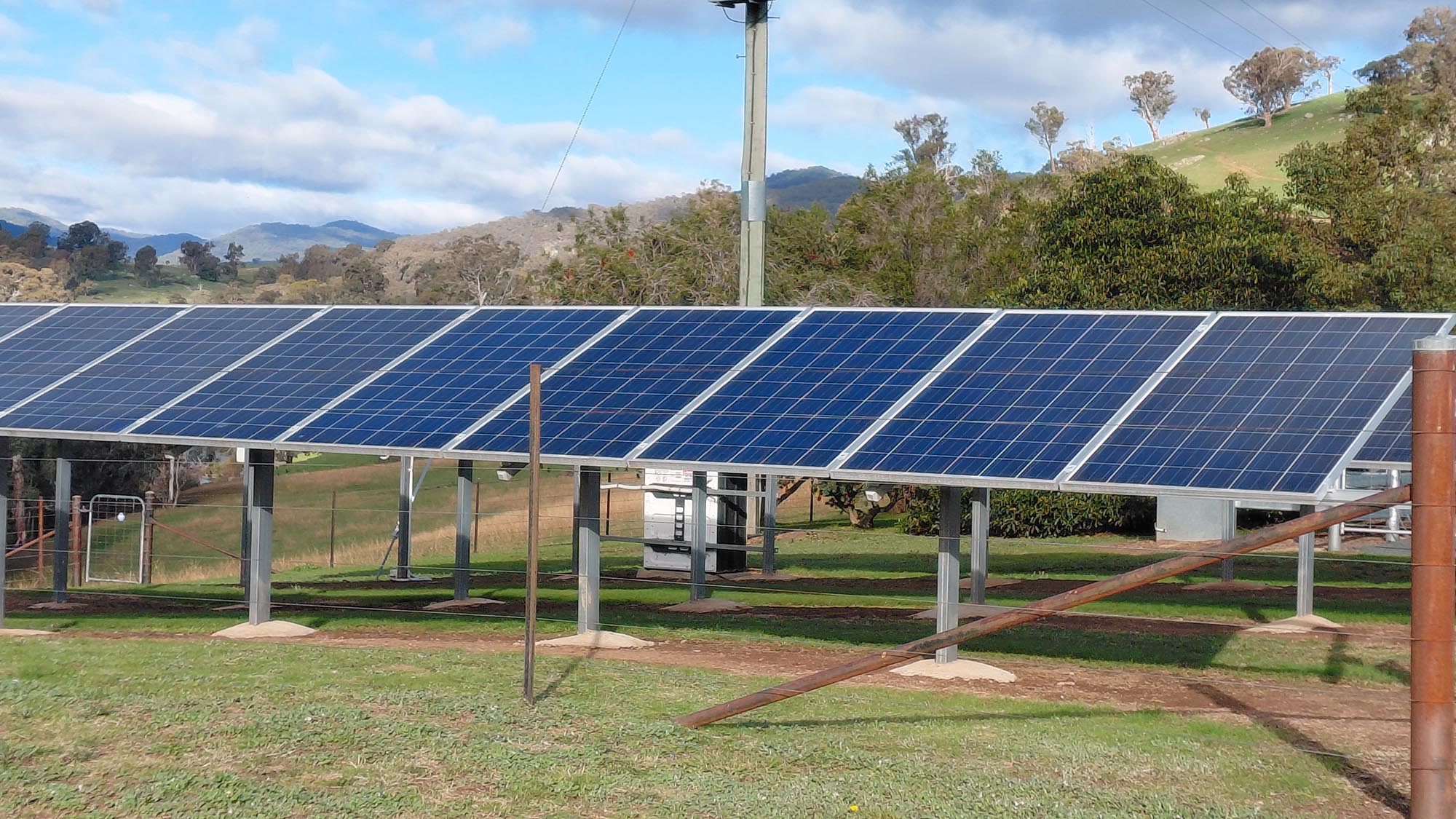 Rows of ground-mounted solar panels at Elm Cottage with the hills behind